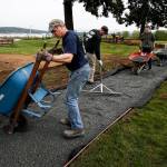 Scott Eastham (left), of Smokey Point, unloads gravel from a wheelbarrow with other volunteers while helping to build a wheelchair accessible trail through Legion Memorial Park in Everett on Saturday, April 29. (Ian Terry / The Herald)