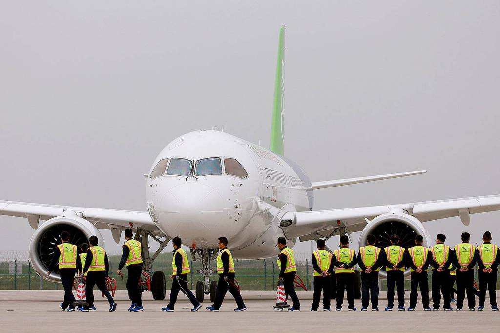 Members of staff stand in front of China&rsquo;s home-grown C919 passenger jet after it landed on its maiden flight at the Pudong International Airport in Shanghai, China, on Friday. (Aly Song/Pool Photo via AP)