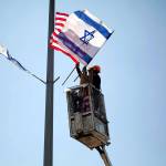 A worker on Tuesday hangs Israeli and American flags on a lamppost along a freeway leading to Jerusalem, days before a planned visit by President Donald Trump. (AP Photo/Ariel Schalit)