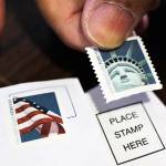 A customer places first class stamps on envelopes at a U.S. Post Office in San Jose, California, in 2011. (AP Photo/Paul Sakuma)