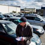 Car dealer K.C. Crandall, of Burlington, jots down notes about a car after test driving it at a dealer auction at Kaman Auctions in Edmonds. (Ian Terry / The Herald)