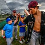 Matthew and Noah Irish look on as Lakewood High School baseball player Morgan Stacey fist-bumps with Jacob Irish as all players leave the fields. (Dan Bates / The Herald)