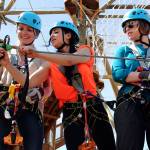 Emily Druschba (left) gets safety instruction from Delana Martinez with Haley Lannom looking on before climbing the course Thursday afternoon in the High Trek Adventures at Paine Field in Everett. (Kevin Clark / The Herald)