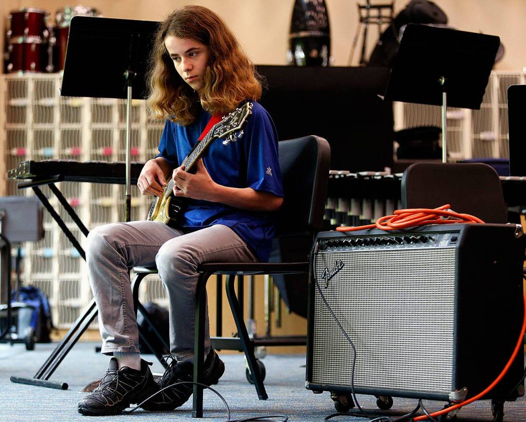Elijah Croyle practices a short while on an electric guitar before joining the bassoon section and the rest of the band Wednesday last week at Valley View Middle School in Snohomish. (Dan Bates / The Herald)