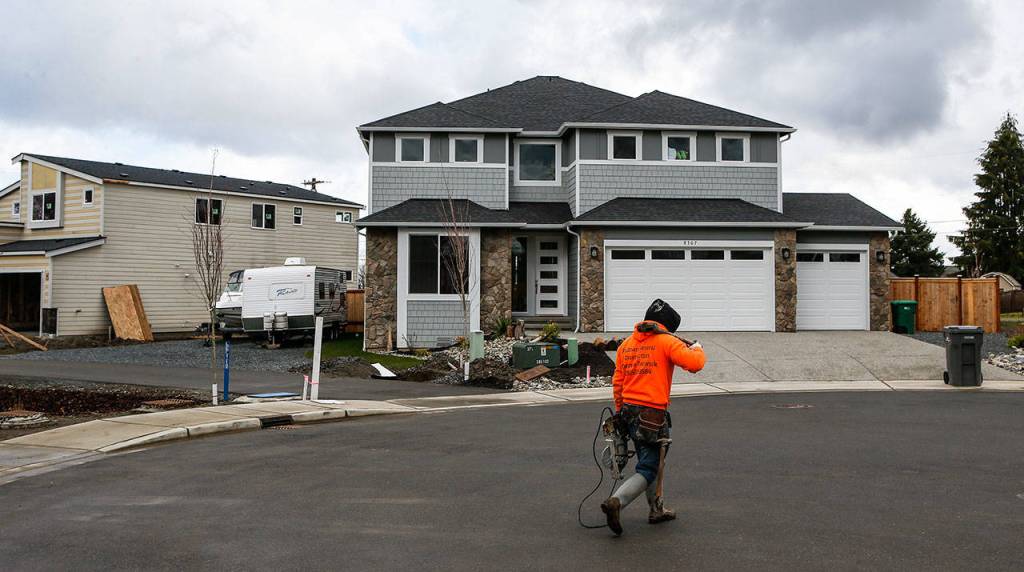A construction worker walks by houses under construction in a cul-de-sac on 8th Pl SEon Wednesday, March 8, 2017 in Lake Stevens, Wa. (Ian Terry / The Herald)