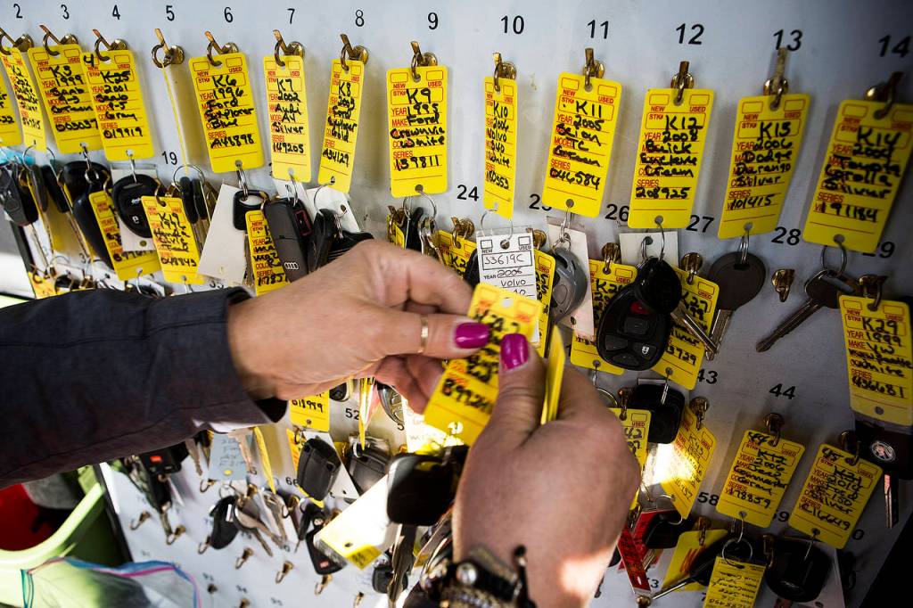 Volunteer Toni Oswalt hangs keys in the parking lot of Kaman Auctions in Edmonds. (Ian Terry / The Herald)