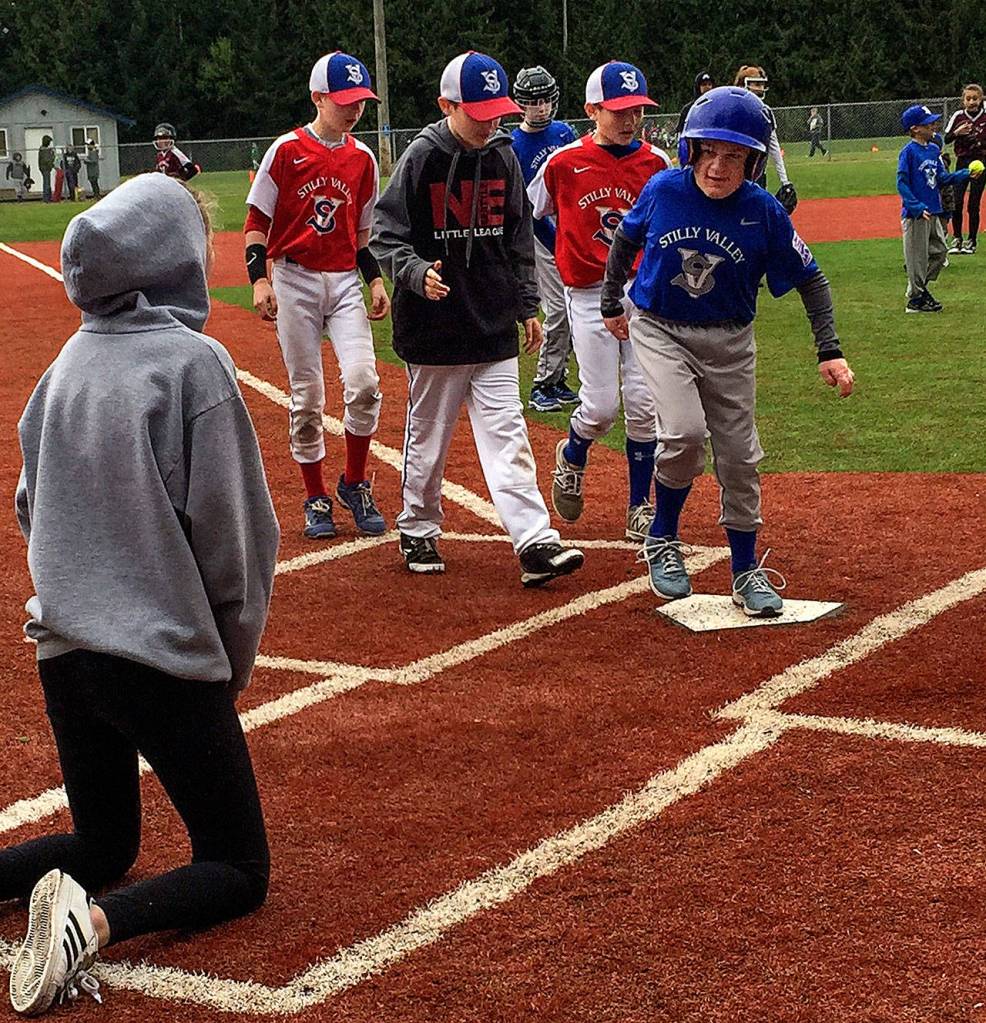 With helpers, including brother Noah right behind him, Jacob Irish steps onto home plate. With Noah are his Stilly Valley Little League Majors teammates Luke Ursino and Jackson Griffin. (Melanie Irish photo)