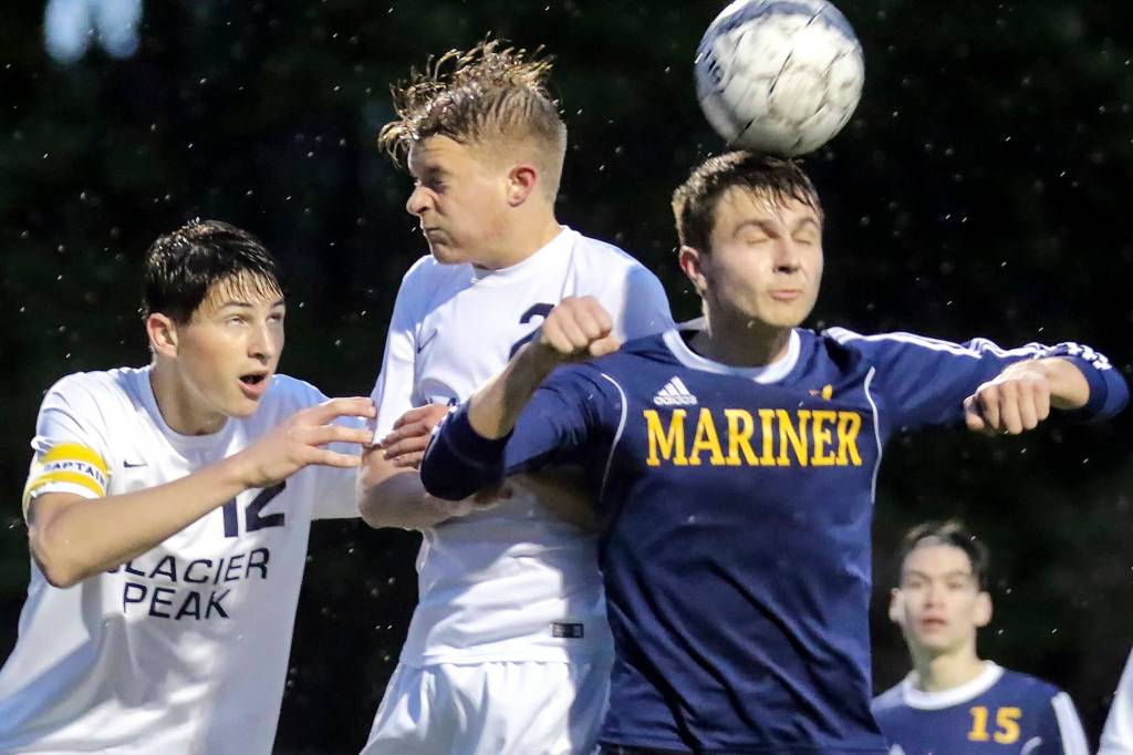 Mariner&rsquo;s Edward Katynskiy heads the ball with Glacier Peak&rsquo;s Camron Miller (left) and Glacier Peak&rsquo;s Kevin Ramsey challenging at Lake Stevens High School on May 11. (Kevin Clark / The Herald)