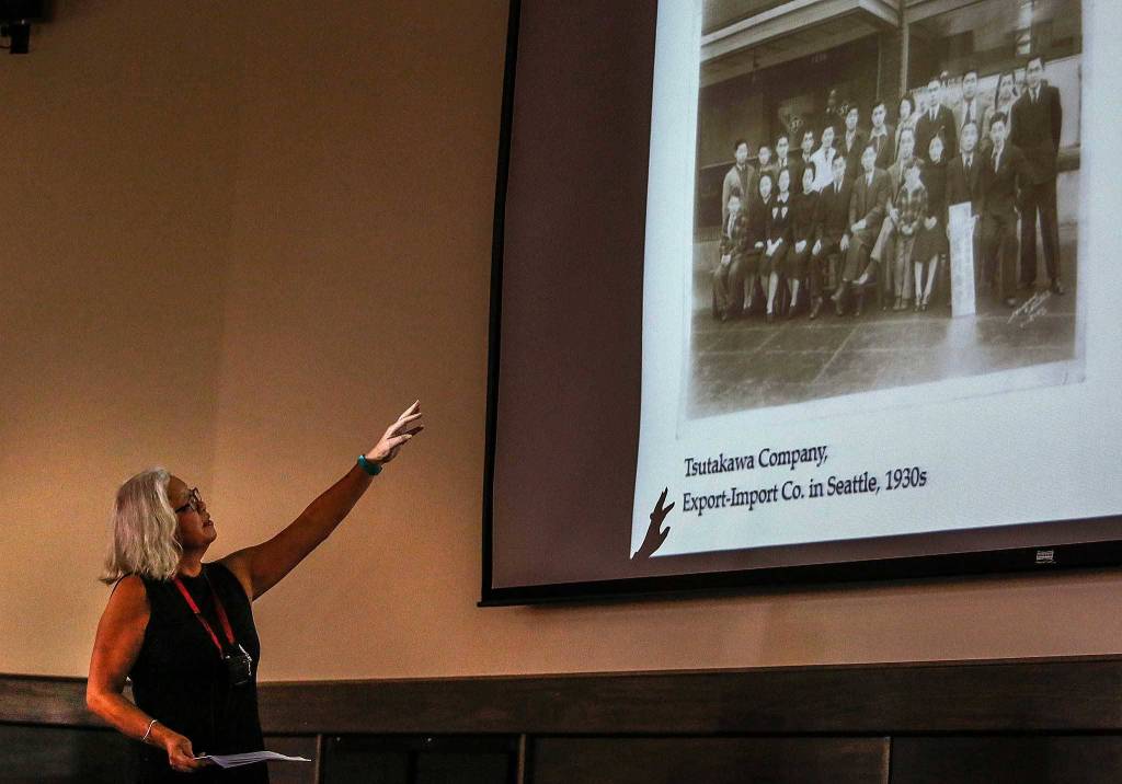 At Everett Community College on May 16, Mayumi Tsutakawa, daughter of acclaimed northwest sculptor George Tsutakawa, talks about her mother&rsquo;s experience in a Japanese internment camp 75 years ago, and her family&rsquo;s history in Seattle&rsquo;s &ldquo;Japantown&rdquo; a century ago. Here she displays a photo and talks about her husband&rsquo;s father&rsquo;s Export-Import Company in Seattle during the 1930s. (Dan Bates / The Herald)