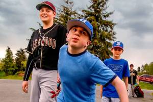 Brothers Matthew Irish, 15 (left), and Noah, 11, follow their older brother, Jacob, 16, as they walk to their car from the baseball field at Lakewood Middle School on Thursday after games were canceled by lightning. Jacob, who was born with life-threatening Hurler syndrome, is playing on a baseball team for the first time. (Dan Bates / The Herald)