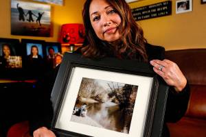 Mayume Carelli&rsquo;s home is filled with images of the people she loves, including the one she is holding of her dad, Dan Varnell at his favorite fishing hole on the Pilchuck River. It is where he was murdered by Gail Brashear in 1996. (Dan Bates / The Herald)