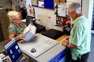 At the Silvana Post Office on Thursday morning, SSA clerk Debbie Nield helps Dwaine Howe, of Camano Island, mail a package. (Dan Bates / The Herald)