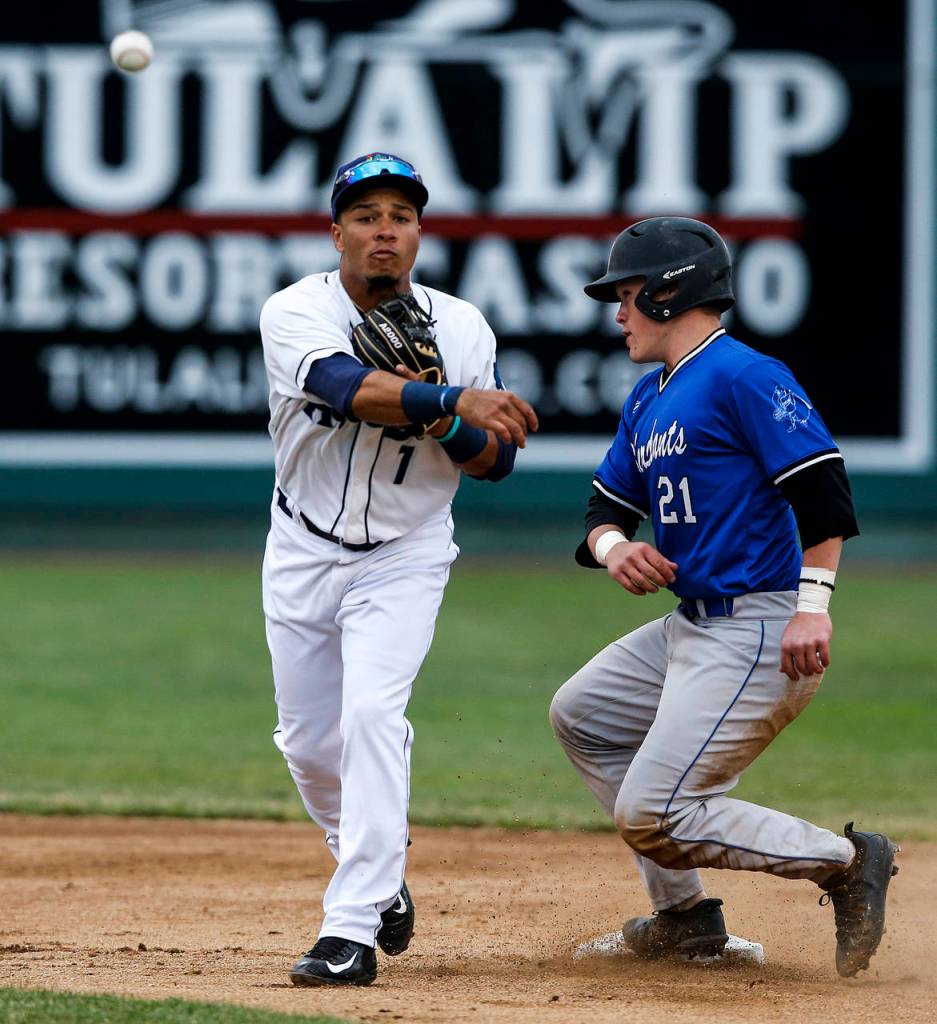 Aquasox infielder Joseph Rosa (left) throws to first base to complete a double play as Merchants runner Matt Thompson slides into second base during the Everett Cup exhibition game on June 13, 2017, at Everett Memorial Stadium. (Ian Terry / The Herald)