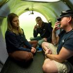 David Lochridge (right) describes diving at great depths to Bonnie Carl and Josh Dean as they sit in the OceanGate sub Cyclops1 submerged in the waters of the Port of Everett Marina on May 18. (Andy Bronson / The Herald)