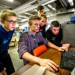 In the Granite Falls Middle School&rsquo;s shop building, manufacturing teacher Kirk Parker (back left) watches 7th and 8th-grade students, Jamieson Haverfield (left) Malachi Caldera, Dylan Klepper, Parker Lembke and Derek Caldart (standing) who are fully engrossed as Caldera, using a computer, sets up the parameters of a laser printer that will enable them to engrave their designs on wood. The building is going to be remodeled next year to better accommodate teaching manufacturing technologies like this. (Dan Bates / The Herald)