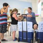 From one of two coolers, Mike Bradshaw-Heiberg hands out brown bag lunches and half-pints of milk as part of the Kids Cafe summer meals program July 1, 2015, in Sultan. (Kevin Clark / Herald file)