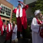 Snohomish High graduate Riley Gagnon (center) finds tries to get a better view to find his family as Analise Bingham (right) calls on the phone after their graduation ceremony at Xfinity Arena on Monday in Everett. (Andy Bronson / The Herald)