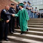 Woodinville High School graduate Esteban Underwood is greeted by Tulalip Police&rsquo;s Jeff Jira along with many other law enforcement officers from various departments at his school&rsquo;s graduation ceremony at Xfinity Arena on Monday, June 19. Underwood&rsquo;s father, a Des Moines police officer, was shot and killed in the line of duty in 2001. (Ian Terry / The Herald)