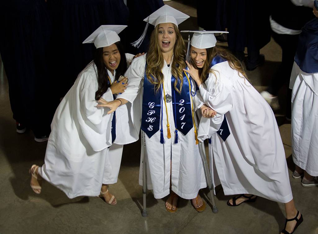 Glacier Peak High School&rsquo;s Rumie Lee (left) and Sara Major (right) pretend to knock over Madeline Mahler, who is on crutches, as they take a picture together before their graduation ceremony at Xfinity Arena on Monday in Everett. (Andy Bronson / The Herald)