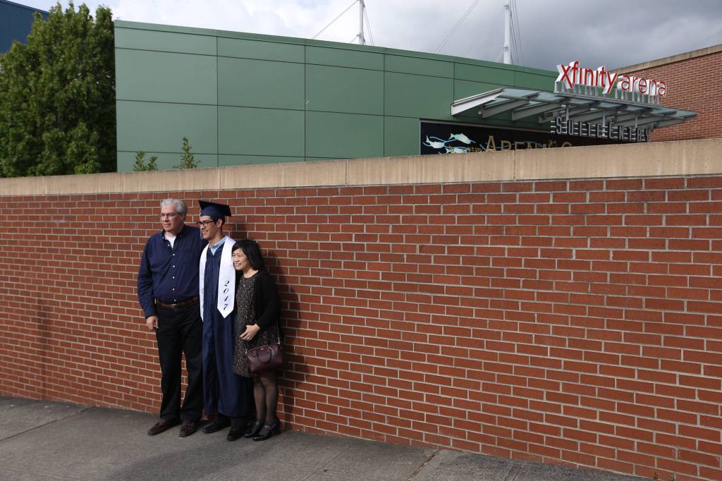 Glacier Peak High School&rsquo;s Abraham Hall has his picture taken with his parents before the start of his graduation ceremony at Xfinity Arena on Monday in Everett. (Andy Bronson / The Herald)