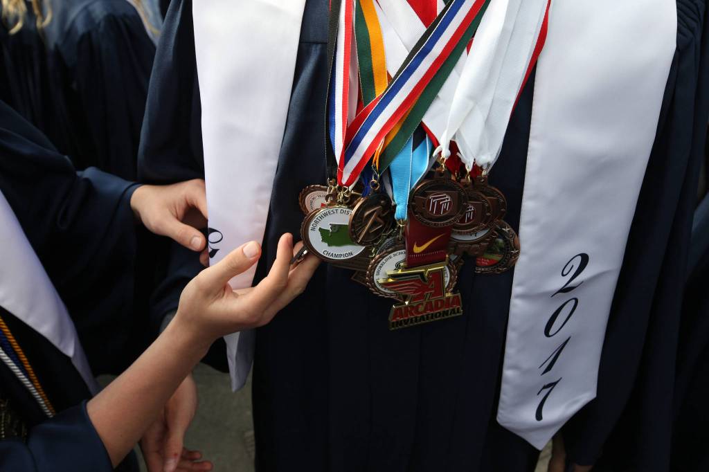 A fellow Glacier Peak High School senior checks out some of the 30-plus medals worn by Chris Bianchini before their graduation ceremony at Xfinity Arena on Monday in Everett. (Andy Bronson / The Herald)