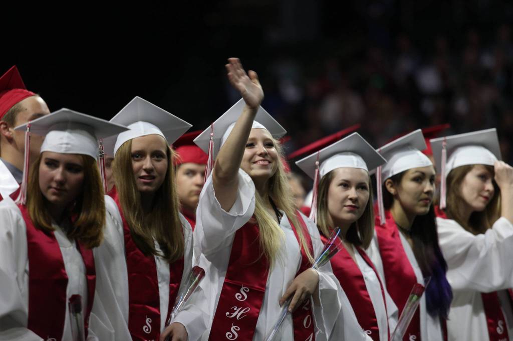 Snohomish High&rsquo;s Mayah Chisa waves to family as she and classmates get seated for their graduation ceremony at Xfinity Arena on Monday in Everett. (Andy Bronson / The Herald)