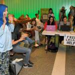 While activists and lawyers at the table at right offer help and information, Hanadi Al-Haj prays in the Tom Bradley International Terminal at Los Angeles International Airport as she waits for her Yemeni mother to arrive from Jordan via Istanbul, on Thursday. (AP Photo/Mark J. Terrill)
