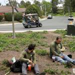 In this 2016 photo, Duncan Wallace drives a golf cart from his house to his golf club as a group of landscape workers take a break in Vista, California. (AP Photo/Gregory Bull, File)