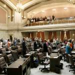 Lawmakers at the House stand during the Pledge of Allegiance on Tuesday in Olympia. The Legislature must send a new two-year budget this week or else risk a partial government shutdown. (Rachel La Corte / Associated Press)