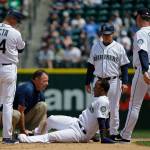 Mariners shortstop Jean Segura (bottom) is examined by trainer Rob Nodine after suffering an injury sliding into second base in the fourth inning of a game against the Rockies on June 1, 2017, in Seattle. (AP Photo/Ted S. Warren)
