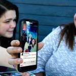 Dakota Mowry shows a picture from her June 8 graduation from AIM High School to her mom, Crystal Scholl, also an AIM graduate.