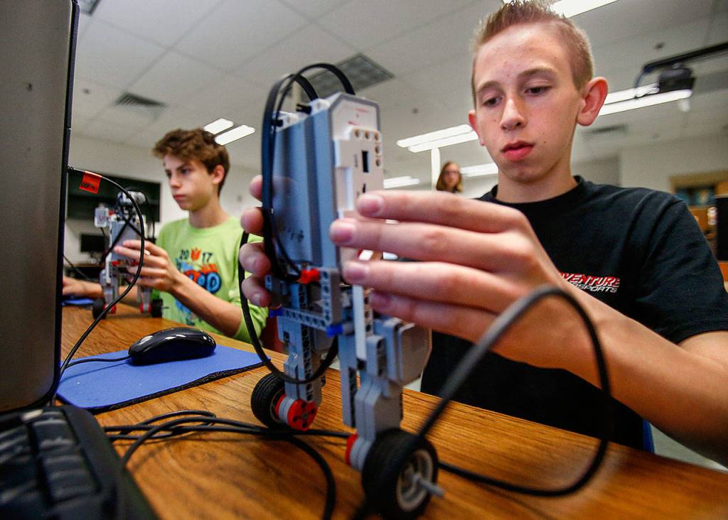 Granite Falls Middle School eighth-graders Howard Wilde (right foreground) and Jason Wad work at programming self-balancing EV3 robots so they will balance in a vertical stance while moving about. (Dan Bates / The Herald)