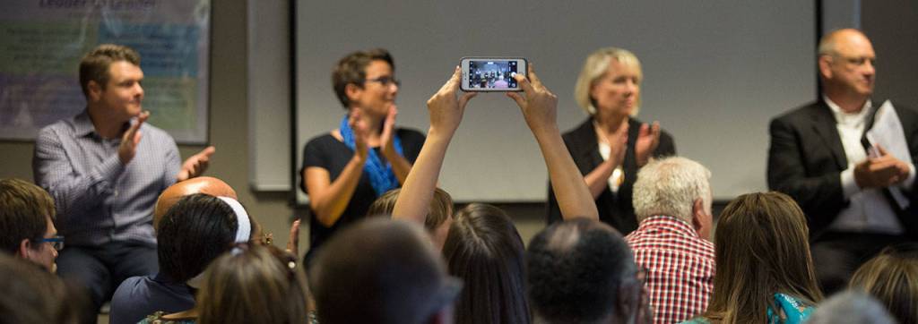 An audience member reaches up to take a photo at the start of Monday&rsquo;s forum for Everett mayoral candidates at the Children&rsquo;s Village on Casino Road. (Andy Bronson / The Herald)