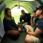 David Lochridge (right) describes diving at great depths to Bonnie Carl (left) and Josh Dean in the OceanGate sub Cyclops I, submerged in the waters of the Port of Everett Marina. (Andy Bronson / The Herald)