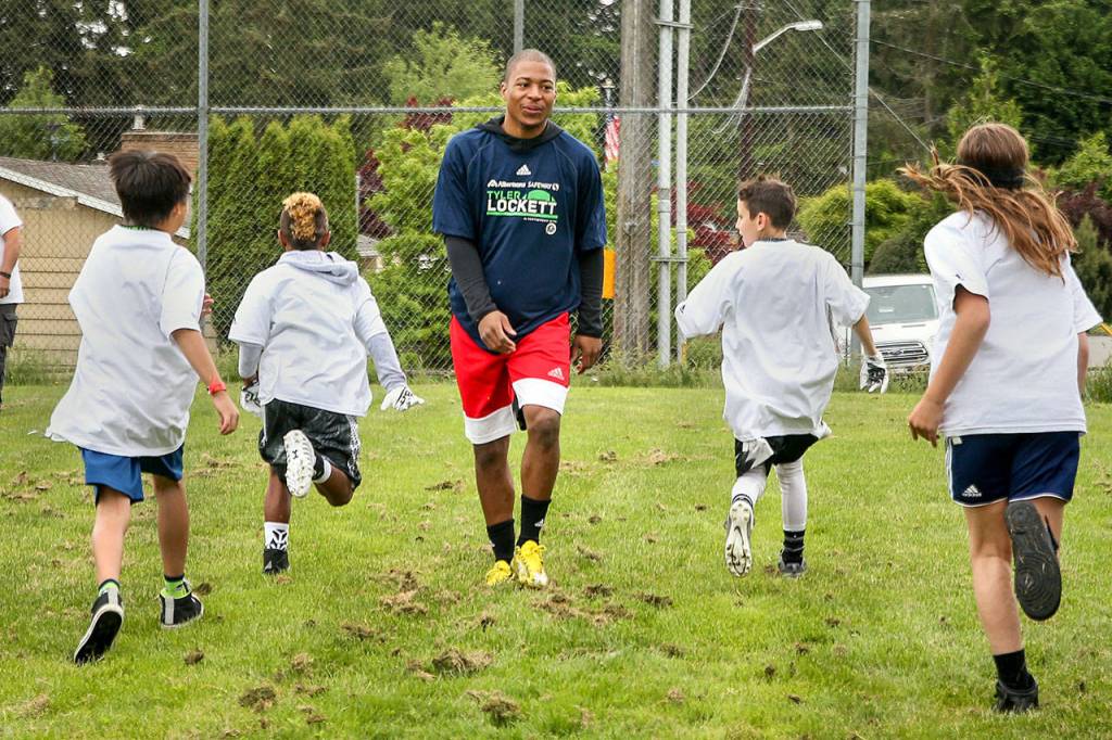 Campers sprint past Seahawks Tyler Lockett Saturday morning at Edmonds-Woodway High School. (Kevin Clark / The Herald)