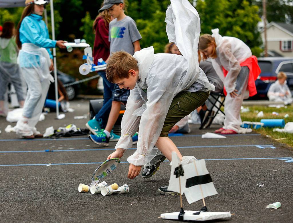 As sixth-grader T.J. Smith reaches for his lightweight wind-driven Rover, a gust of wind catches his space suit at a mock Mars colony he and fellow sixth-graders constructed outside Haller Middle School in Arlington on Monday. The Rover T.J. designed and built appeared to be doing well in wind-power-distance competition. (Dan Bates / The Herald)