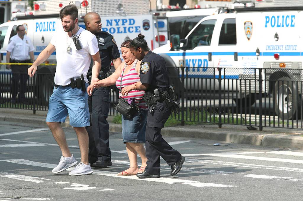 Police help people cross the street outside the Bronx Lebanon Hospital in New York after a gunman opened fire there on Friday. (AP Photo/Mary Altaffer)