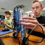 Granite Falls Middle School eighth-graders Howard Wilde (right foreground) and Jason Wad work at programming EV3 robots so they will balance in a vertical stance while moving about. (Dan Bates / The Herald)
