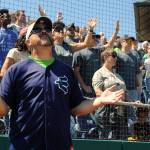 Wearing an AquaSox jersey and hat, New Life Church Lead Pastor Jim Romack prays along with members of the church during a song played by the church&rsquo;s band at the One Day event held at Everett Memorial Stadium Ballfield on Sunday. (Doug Ramsay / for The Herald)