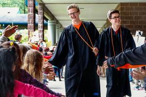 Monroe High School graduating seniors, including Ethan Medlin (left) and classmate Dawson Eifert face a gauntlet at Chain Lake Elementary School in their graduation gowns Friday, for all the young students to see. Medlin,18, who attended Chain Lake Elementary not so long ago, has been granted a full-ride scholarship to Harvard. (Dan Bates / The Herald)