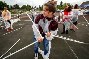 Kadie Harrett (center) is not just caught up in her work, but might have even torn her space suit as she and classmates attempt construction of a Mars habitat Monday outside Haller Middle School in Arlington, where sixth-graders spent the day building a mock Mars colony. (Dan Bates / The Herald)