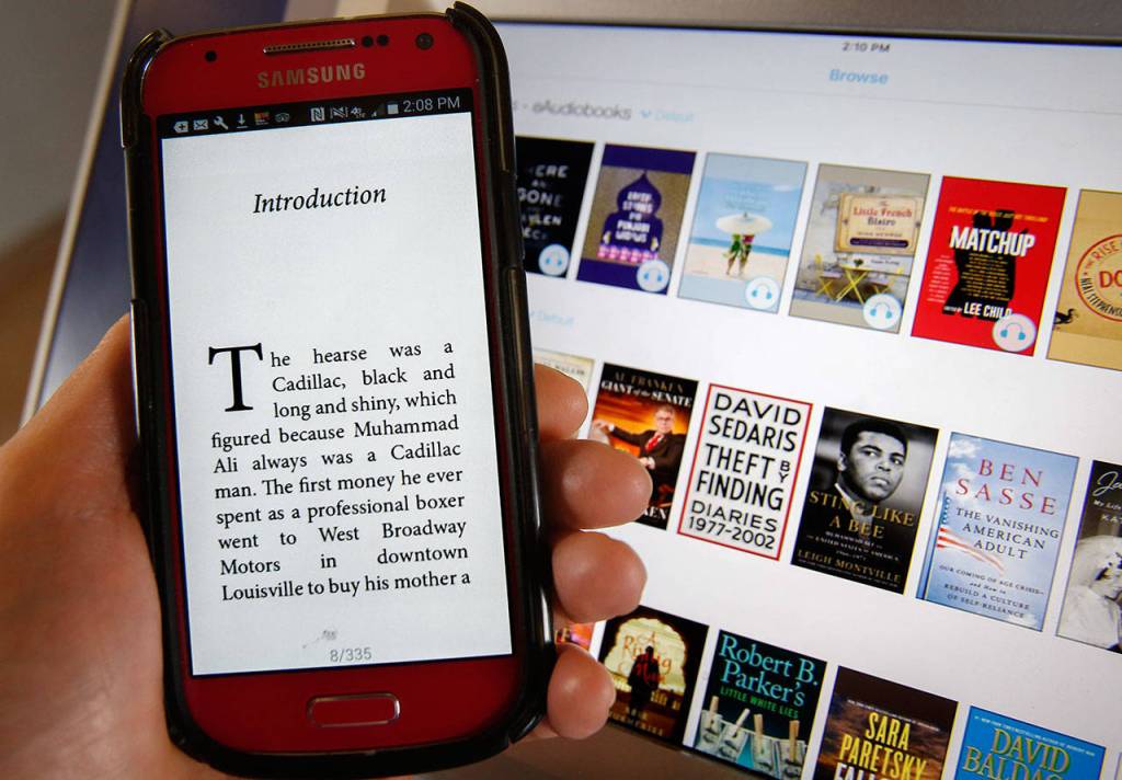 The opening page of &ldquo;Sting Like a Bee,&rdquo; a Muhammad Ali biography, shows on the cellphone of a user of the Cloud Library ebook kiosk recently installed at Everett Station. The Everett Public Library&rsquo;s kiosk is available for anyone to use without charge. In the background are images of books available on the kiosk, including &ldquo;Sting Like a Bee.&rdquo; (Dan Bates / The Herald)