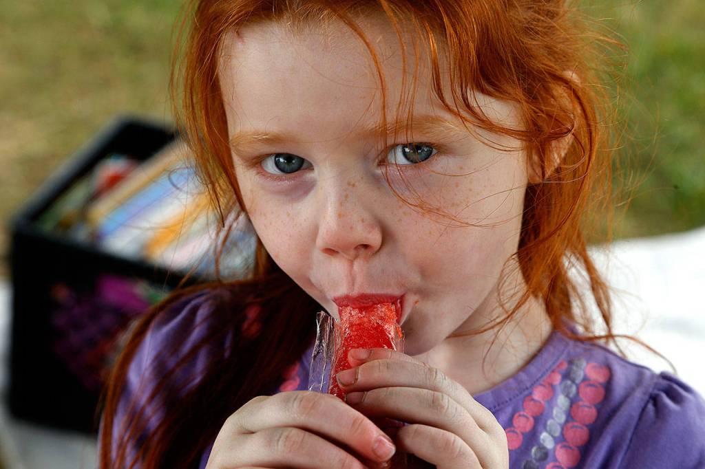 Eliana Puterbaugh, 4, takes a bite from her Otter Pops, which were given to all the kids attending the book event. (Dan Bates / The Herald)