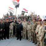 Iraq prime minister Haider al-Abadi raises the national flag on Monday as he addresses forces from a small base on the edge of Mosul&rsquo;s Old City. Al-Abadi declared victory against the Islamic State group in the northern city following nine months of grueling urban combat. (Iraqi Prime Minister&rsquo;s Media Office via AP)