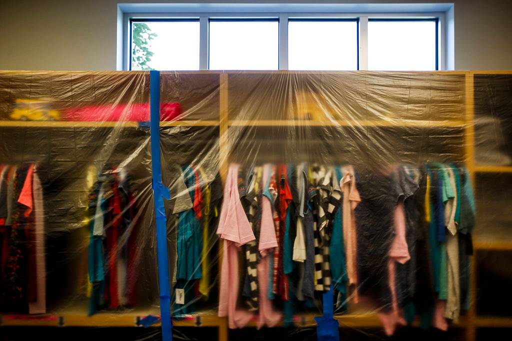 Salvaged clothing is protected from dust by plastic sheets at the Assistance League of Everett on July 5. (Ian Terry / The Herald)