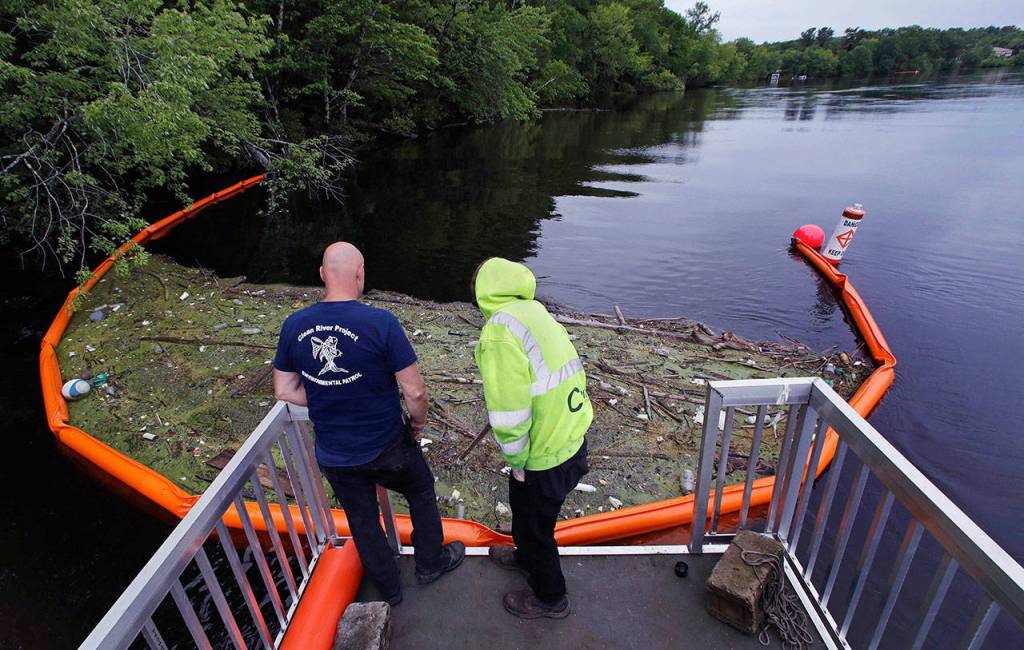 In this Wednesday, June 7, 2017 photo, activist Rocky Morrison, left, and volunteer Dalton Abbott, of the &ldquo;Clean River Project&rdquo; examine a boom filled with waste collected from a recovery boat on the Merrimack River in Chelmsford, Mass. Syringes left by drug users amid the heroin crisis are turning up everywhere. They hide in weeds along hiking trails and in playground grass, get washed into rivers and onto beaches, and lie scattered about in baseball dugouts and on sidewalks and streets. There are reports of children finding them and getting poked. (AP Photo/Charles Krupa)