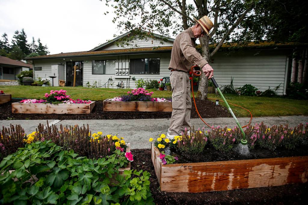 Orval Heath waters his flowers outside his home in the Warm Beach Senior Community on July 20. (Ian Terry / The Herald)