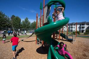 Led by local Marysville YMCA leaders, Kalliyaha Clark, 7, follows Curtsey Jackson, 10, down a slide during a relay race at the Cedars on 67th apartment complex on Wednesday, July 26, 2017 in Marysville, Wa. (Andy Bronson / The Herald)