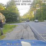 This dashboard camera image released by the Maine State Police shows a man strolling down a street in Hollis, Maine. Police said he was wearing a clown mask with a machete taped to his amputated arm. (Maine State Police via AP)
