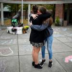 Friends Mariela McNeal (left), 15, and Lauren Crossley, 14, hug near the entrance of Jackson High School where friends and family gathered Thursday to write messages of remembrance for three teens killed in a car crash in Lynnwood early Wednesday. All three who were killed were students at Jackson High School. (Ian Terry / The Herald)